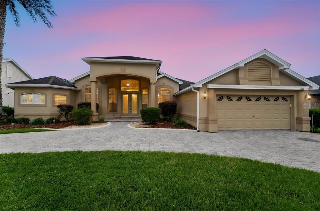A tan single-story house with a paved driveway and a two-car garage at sunset — 1413 CANAL POINT ROAD, LONGWOOD, FL