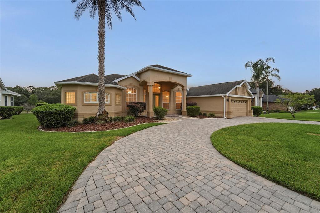 A tan stucco house with a paved driveway and a palm tree in the front yard — 1413 CANAL POINT ROAD, LONGWOOD, FL