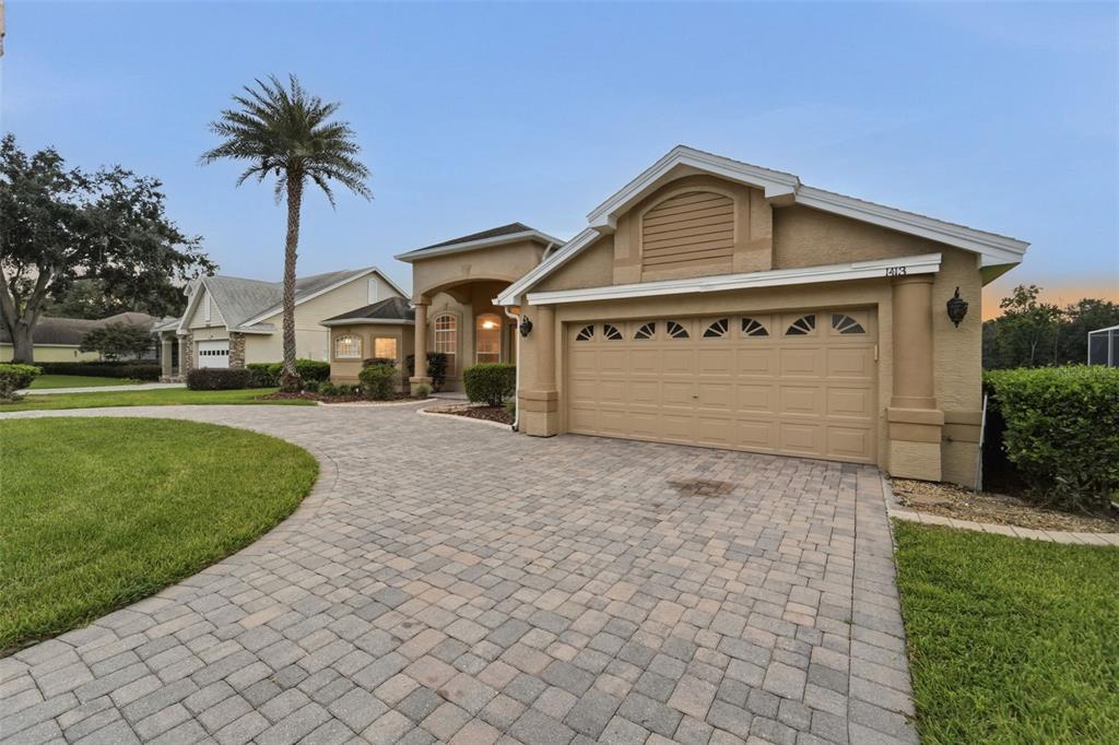 A tan single-story house features a paved driveway, a two-car garage, and a palm tree — 1413 CANAL POINT ROAD, LONGWOOD, FL