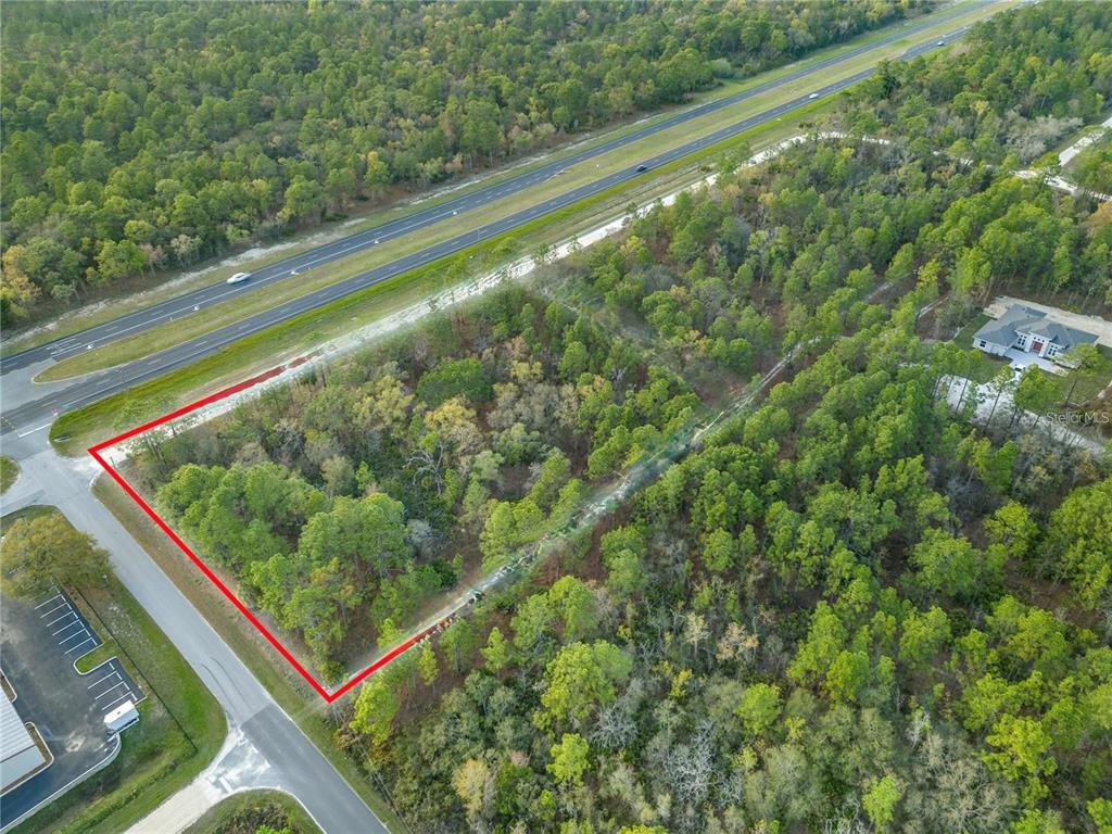 An aerial view shows a wooded, rectangular lot outlined in red next to a highway — 17416 NICASIO JAY AVENUE, WEEKI WACHEE, FL
