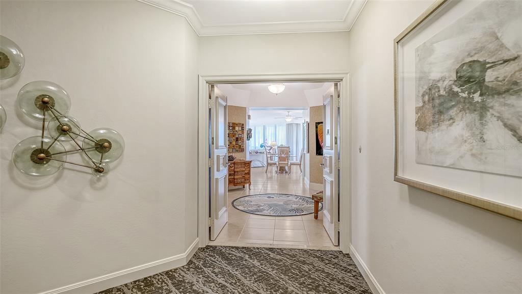A view through double doors into a tiled room with a dining set and rug — 535 SANCTUARY DRIVE UNIT A401, LONGBOAT KEY, FL