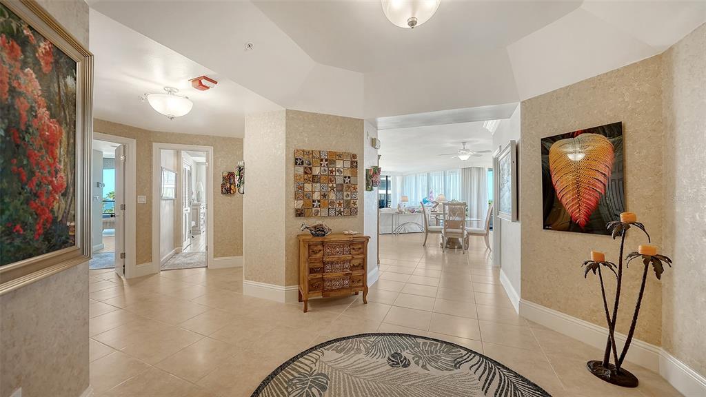 A tiled foyer leads into a bright living area with a decorative wall art piece — 535 SANCTUARY DRIVE UNIT A401, LONGBOAT KEY, FL