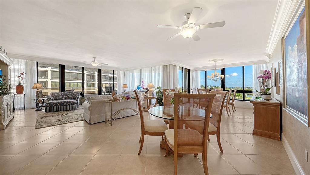 A bright, open-concept living and dining area features tile floors, ceiling fans, and floor-to-ceiling windows — 535 SANCTUARY DRIVE UNIT A401, LONGBOAT KEY, FL