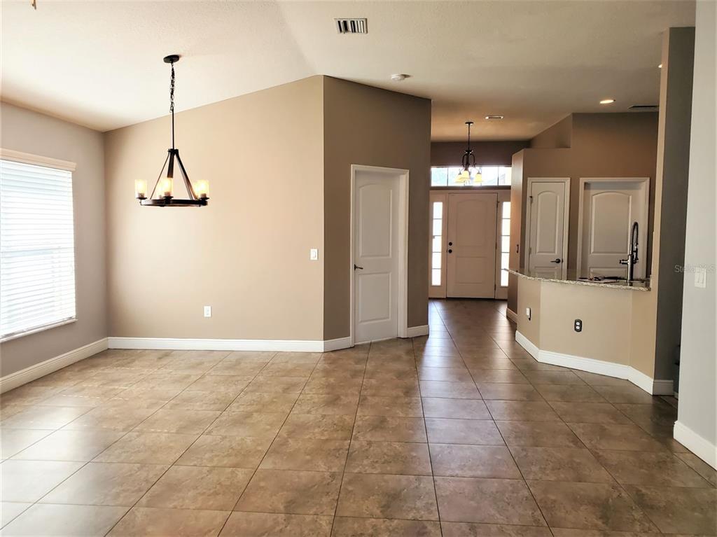 A dining area with tile flooring, a chandelier, and an open view toward the entryway — 10737 STANDING STONE DRIVE, WIMAUMA, FL