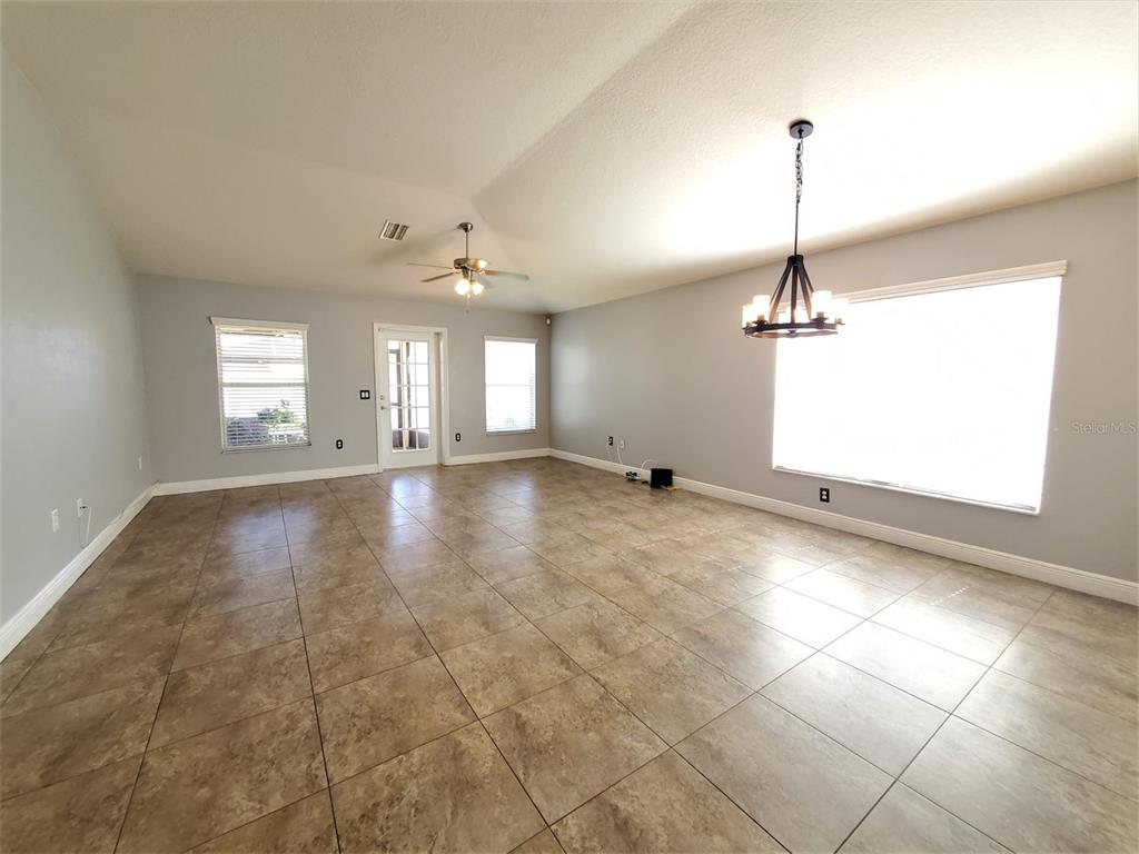 An empty room with light gray walls, tile flooring, a ceiling fan, and a chandelier — 10737 STANDING STONE DRIVE, WIMAUMA, FL