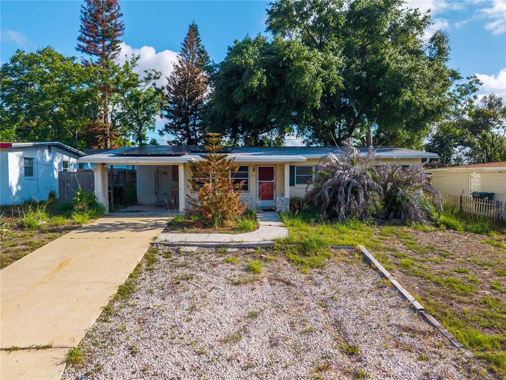 A single-story house with a gravel front yard, a concrete driveway, and a carport — 6031 W. RIDGEWOOD AVENUE, ORLANDO, FL