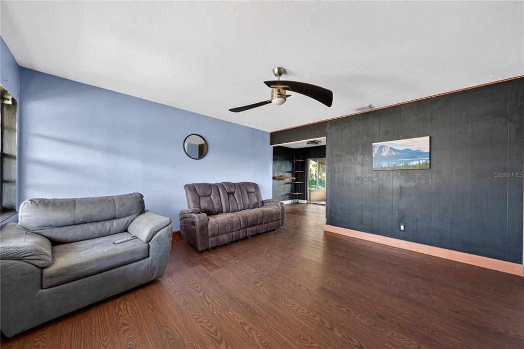 A living room features a blue wall, a black paneled wall, and dark wood flooring — 6031 W. RIDGEWOOD AVENUE, ORLANDO, FL