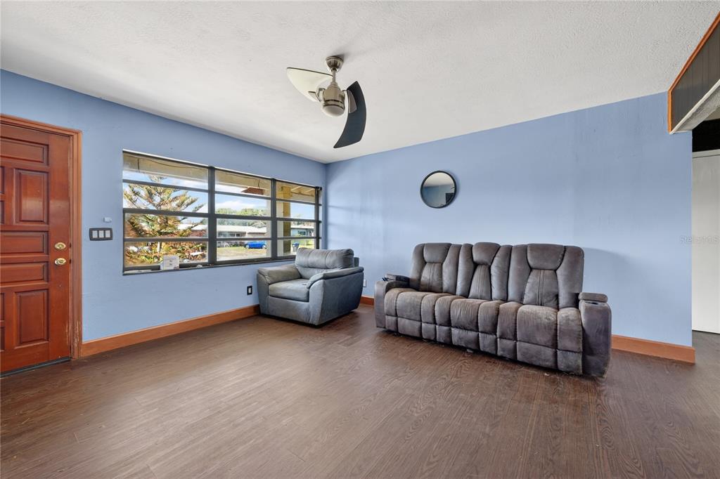 A living room with blue walls, dark wood flooring, a sofa, and an armchair — 6031 W. RIDGEWOOD AVENUE, ORLANDO, FL