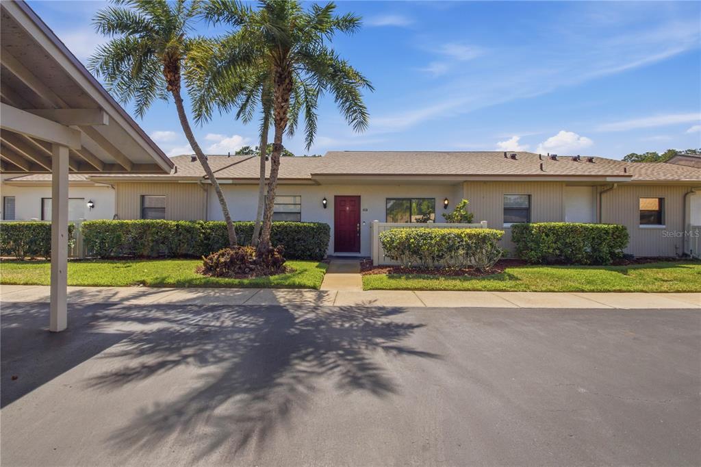A single-story residential building with a red front door, palm trees, and a covered carport — 260 MICHAELS CIRCLE, OLDSMAR, FL