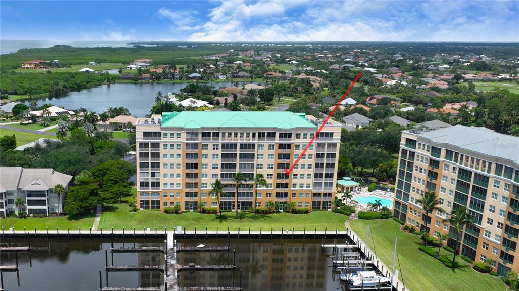An aerial view shows a multi-story apartment building with a red arrow pointing toward it — 2060 MATECUMBE KEY ROAD UNIT 2402, PUNTA GORDA, FL