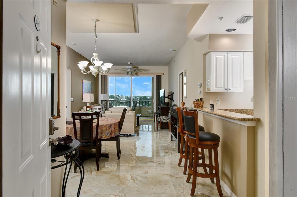 An open-concept living and dining area features marble floors, a breakfast bar, and balcony views — 2060 MATECUMBE KEY ROAD UNIT 2402, PUNTA GORDA, FL