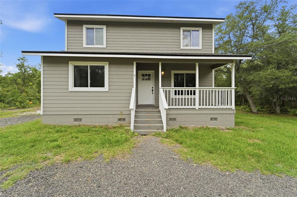 A two-story house with gray siding, a front porch, and a gravel driveway — 41707 ASPEN ST, EUSTIS, FL