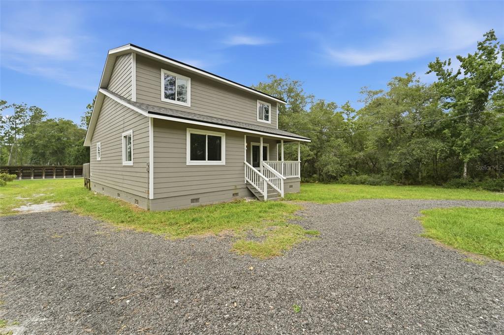 A two-story house with gray siding and a front porch sits on a gravel lot — 41707 ASPEN ST, EUSTIS, FL