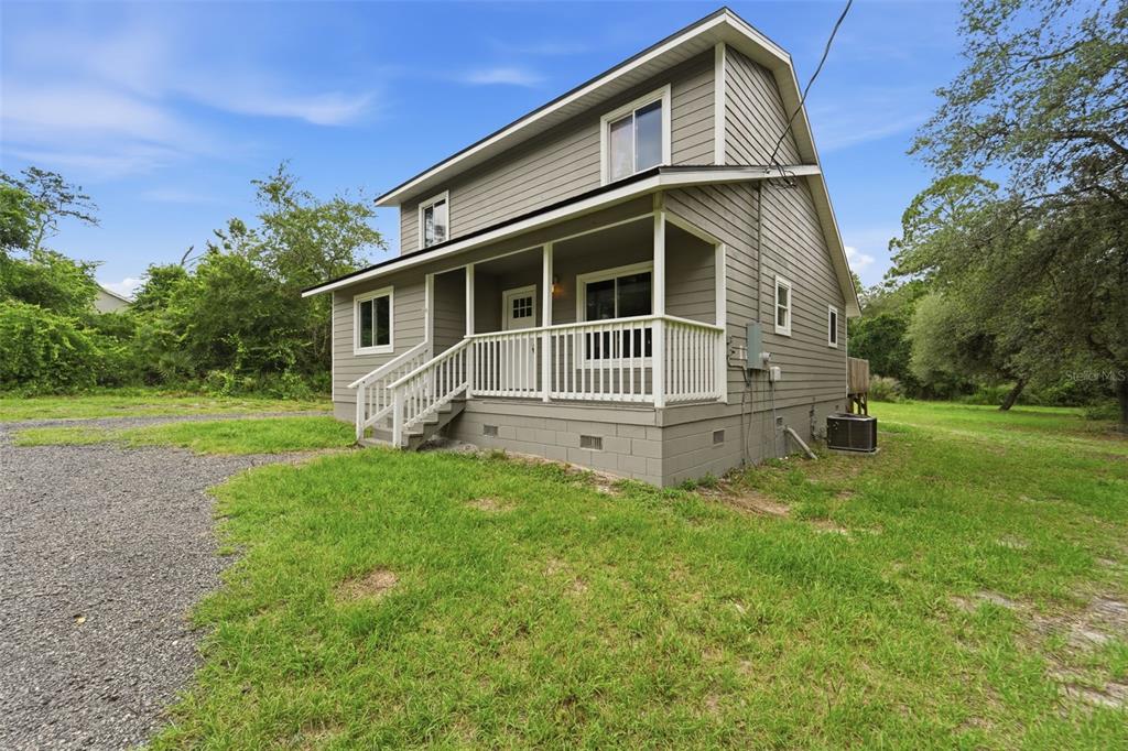 A two-story house with gray horizontal siding and a covered front porch sits on grass — 41707 ASPEN ST, EUSTIS, FL