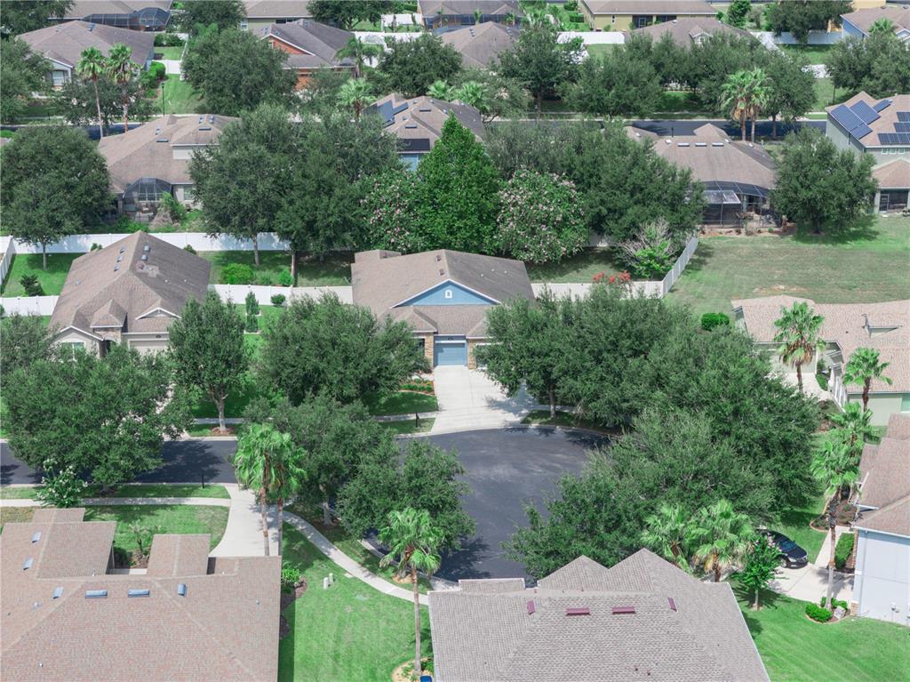 A blue single-story house with a stone facade, a three-car garage, and a sunset sky — 112 PECORRI COURT, AUBURNDALE, FL