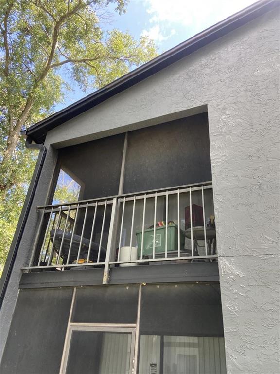 A view of an upper-level screened-in balcony with a metal railing and gray stucco siding — 202 RIVERBEND DRIVE UNIT 204, ALTAMONTE SPRINGS, FL