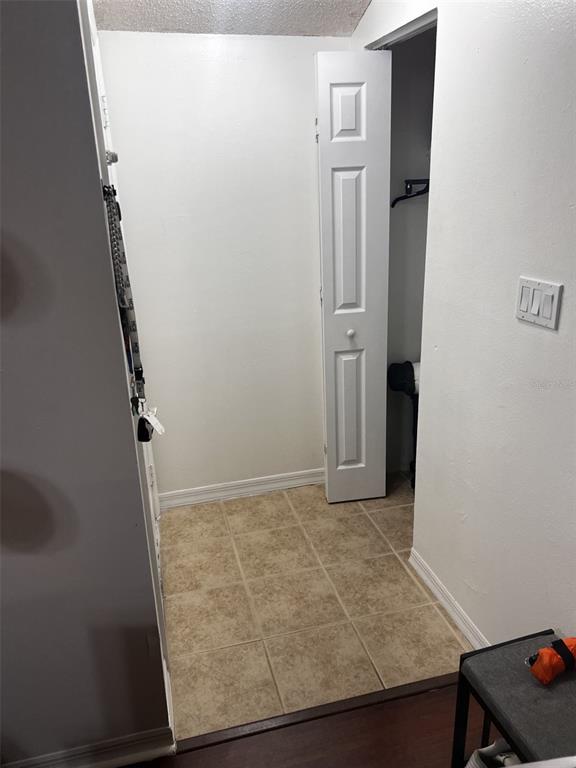 A small entryway features beige tiled flooring, white walls, and a white bifold closet door — 202 RIVERBEND DRIVE UNIT 204, ALTAMONTE SPRINGS, FL