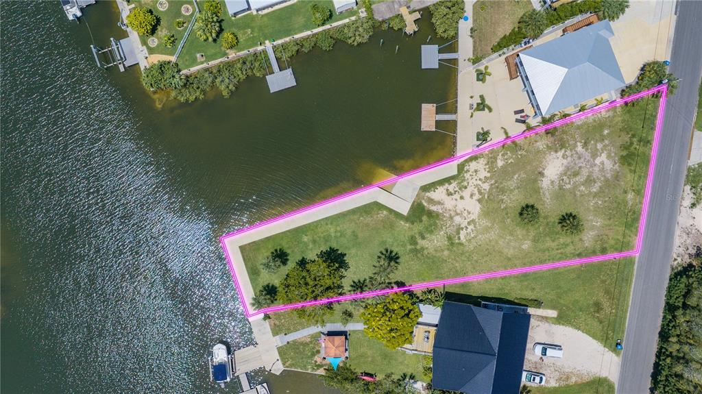 An aerial view shows a vacant waterfront lot outlined in pink next to a residential street — 3616 FLAMINGO BOULEVARD, HERNANDO BEACH, FL