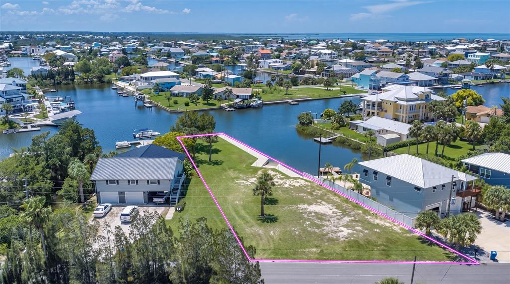 An aerial view shows a vacant waterfront lot outlined in pink between two residential houses — 3616 FLAMINGO BOULEVARD, HERNANDO BEACH, FL