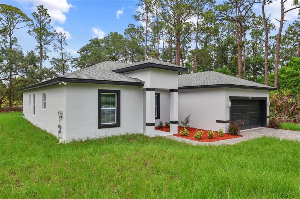 A single-story white house with a dark roof, black trim, and a front-facing garage — 2580 PLUMOSA DRIVE, INDIAN LAKE ESTATES, FL