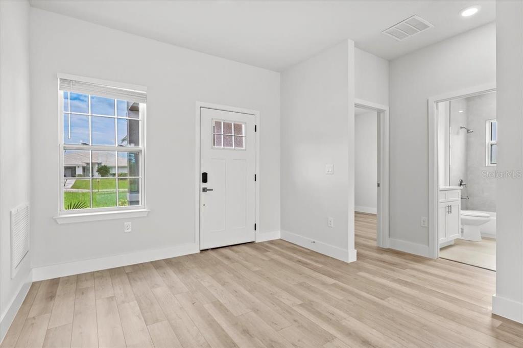 A bright room with light wood-look flooring, a white door, and an attached bathroom — 2580 PLUMOSA DRIVE, INDIAN LAKE ESTATES, FL