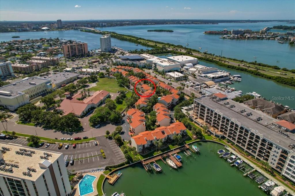 An aerial view shows a residential complex with orange-roofed townhomes near a marina and water — 240 WINDWARD PASSAGE UNIT 702, CLEARWATER, FL