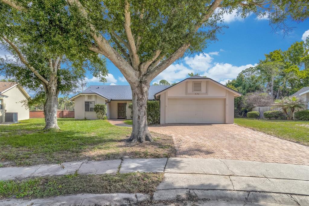 A single-story house with a beige exterior, a two-car garage, and a brick paver driveway — 3152 S HORIZON PLACE, OVIEDO, FL