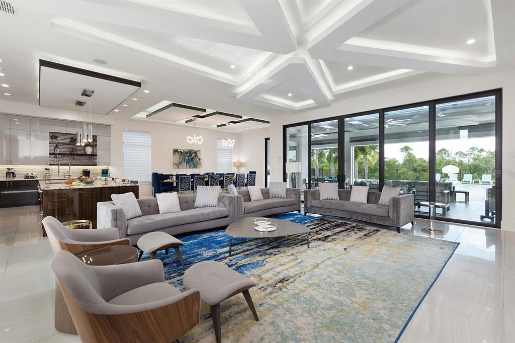 A spacious, modern open-concept living room features a large blue area rug, grey sofas, and floor-to-ceiling windows — 751 GOLDEN BEAR DRIVE, REUNION, FL