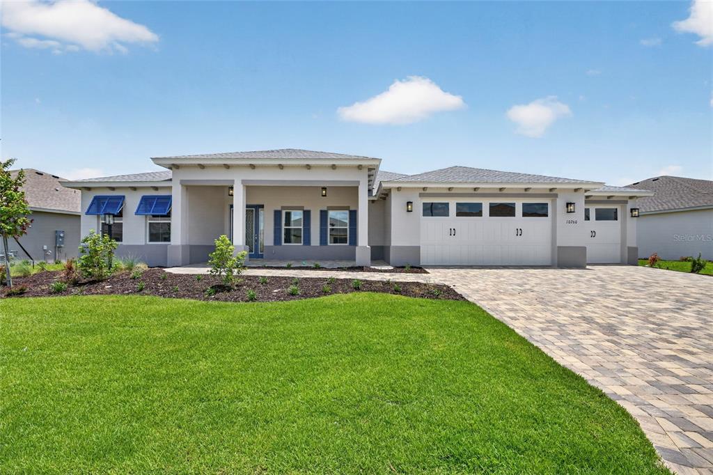 A single-story house with a paved driveway, three-car garage, and blue shutters on the windows — 10260 SW 84TH STREET ROAD, OCALA, FL