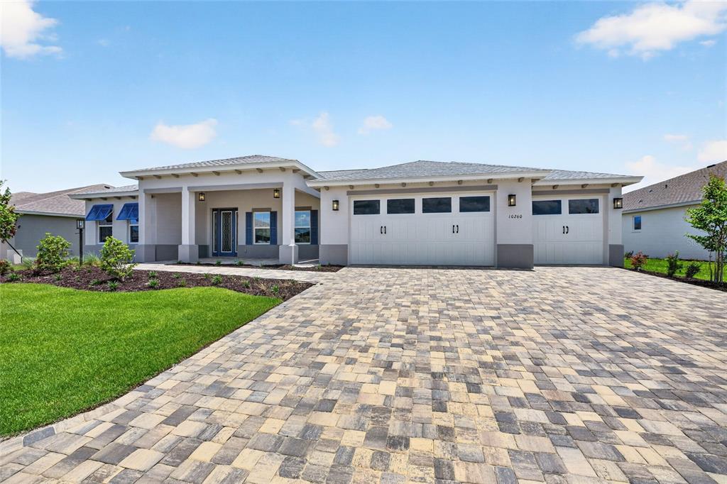 A single-story house features a paved driveway, a three-car garage, and a covered front porch — 10260 SW 84TH STREET ROAD, OCALA, FL