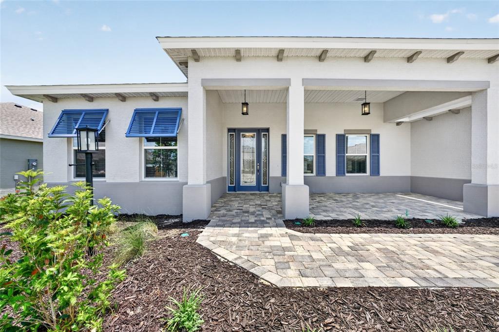 The exterior of a single-story house features a paved walkway, blue shutters, and a covered porch — 10260 SW 84TH STREET ROAD, OCALA, FL