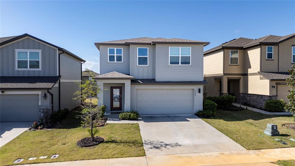 A two-story suburban house with light gray siding, a two-car garage, and a concrete driveway — 2149 TREASURE HILL STREET STREET, MINNEOLA, FL