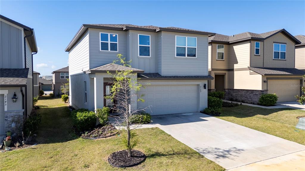 A two-story suburban house with light gray siding, a two-car garage, and a concrete driveway — 2149 TREASURE HILL STREET STREET, MINNEOLA, FL
