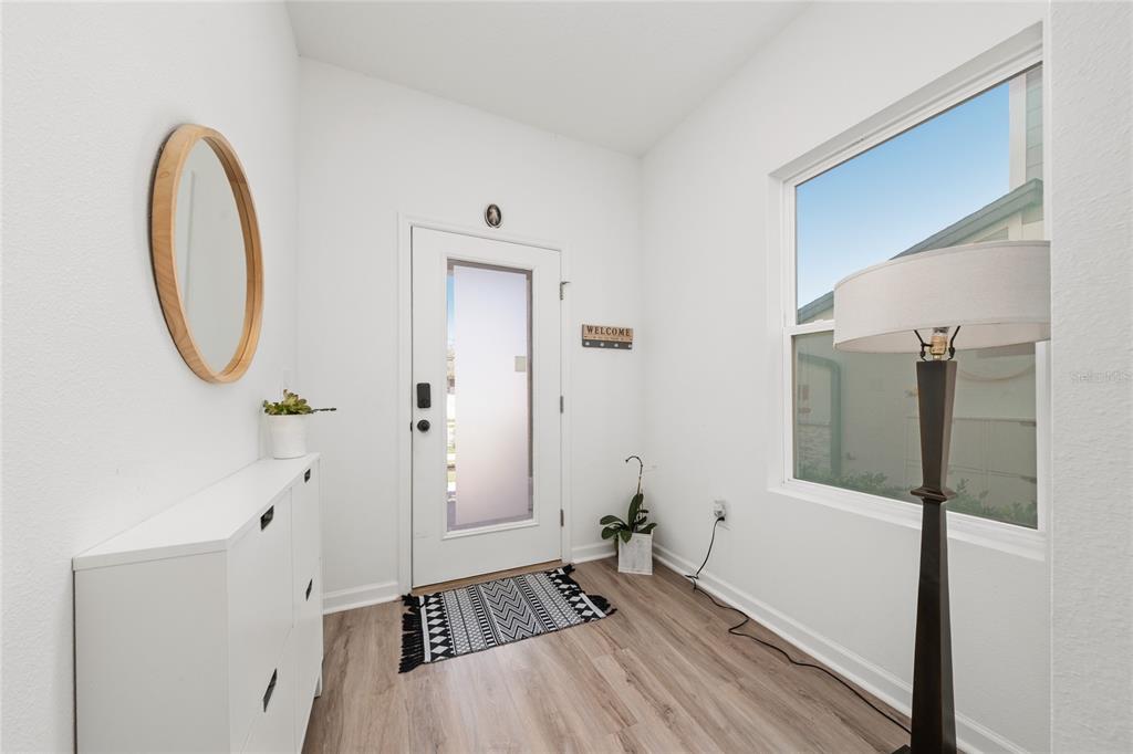 A bright entryway features white walls, wood-look flooring, a white cabinet, and a front door — 2149 TREASURE HILL STREET STREET, MINNEOLA, FL