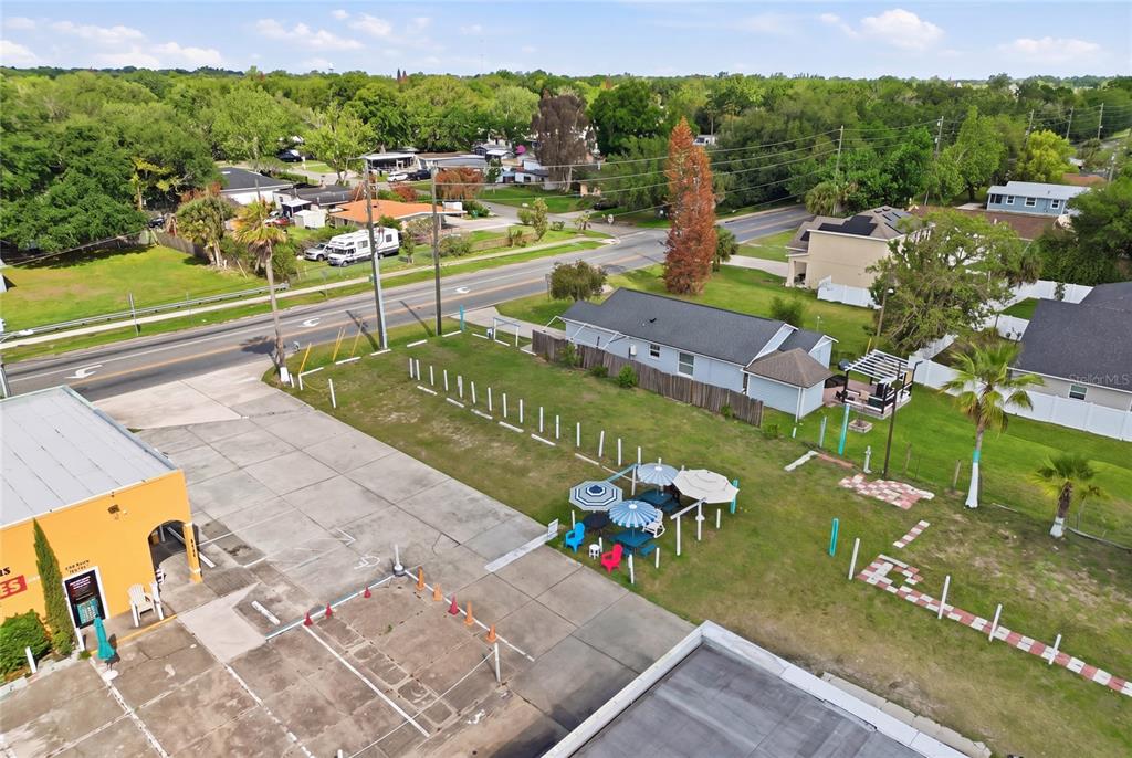 An aerial view shows a paved parking lot with outdoor seating next to a grassy lot — 0 9TH STREET, WINTER GARDEN, FL