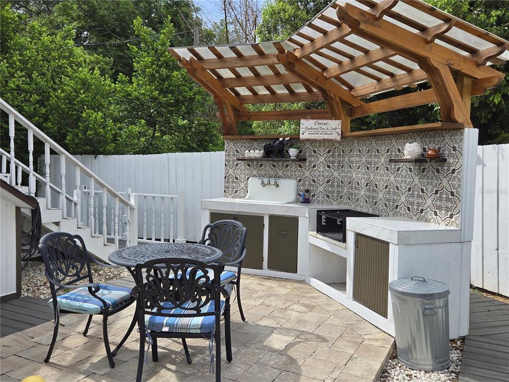 An outdoor patio features a tiled kitchen area with a sink, grill, and wooden pergola — 1690 S 10TH STREET UNIT D, HAINES CITY, FL
