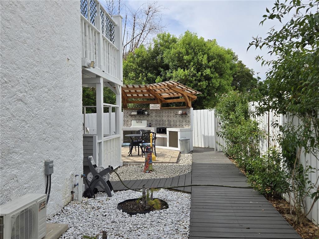 A backyard features a wooden walkway, a white gravel area, and a covered outdoor kitchen — 1690 S 10TH STREET UNIT D, HAINES CITY, FL