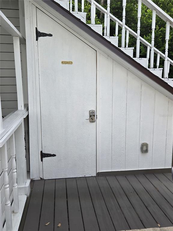A white door with a keypad lock is located under an outdoor wooden staircase — 1690 S 10TH STREET UNIT D, HAINES CITY, FL