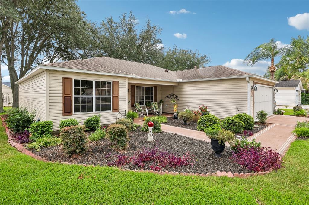 A single-story house with beige siding, brown shutters, a concrete walkway, and landscaped front yard — 3495 AUBURNDALE AVENUE, THE VILLAGES, FL