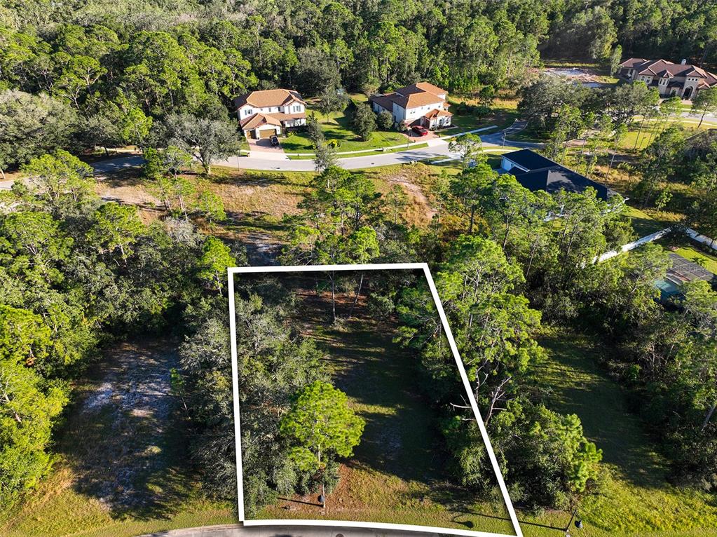 An aerial view shows a vacant, wooded residential lot outlined in white near a suburban street — 7180 OAK GLEN TRL, ST CLOUD, FL