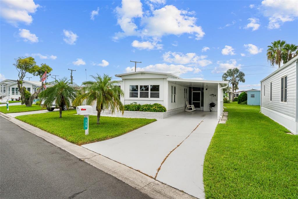 A single-story manufactured home with a white exterior, a concrete driveway, and palm trees — 136 LAKEVIEW DR. DRIVE, PALMETTO, FL