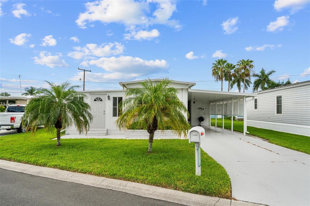 A single-story manufactured home with a white exterior, a carport, and two palm trees — 136 LAKEVIEW DR. DRIVE, PALMETTO, FL
