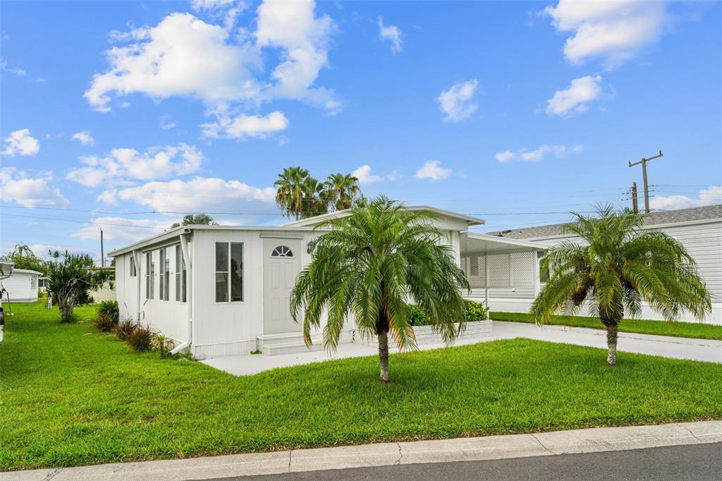 A white mobile home with a palm tree in the front yard under a blue sky — 136 LAKEVIEW DR. DRIVE, PALMETTO, FL