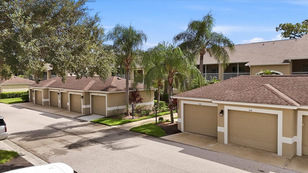 An exterior view of a residential complex featuring several tan garages with brown shingled roofs — 5221 MAHOGANY RUN AVENUE UNIT 224, SARASOTA, FL