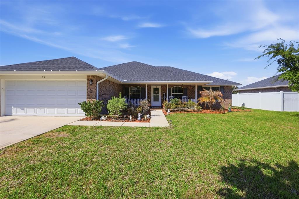 A swimming pool with a sun shelf is enclosed by a screened lanai and fence — 26 NOAH BOULEVARD, FLAGLER BEACH, FL