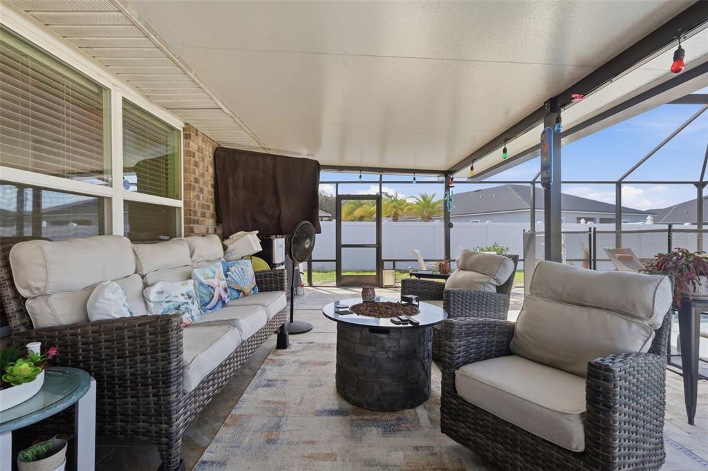 A covered patio features wicker furniture, a fire pit, and a screened-in backyard view — 26 NOAH BOULEVARD, FLAGLER BEACH, FL