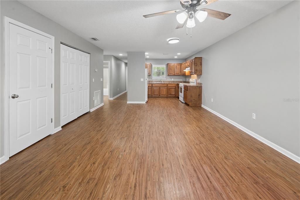 An open-concept kitchen and living area features wood-look flooring, gray walls, and wood cabinetry — 226 BRADFORD DRIVE, STARKE, FL