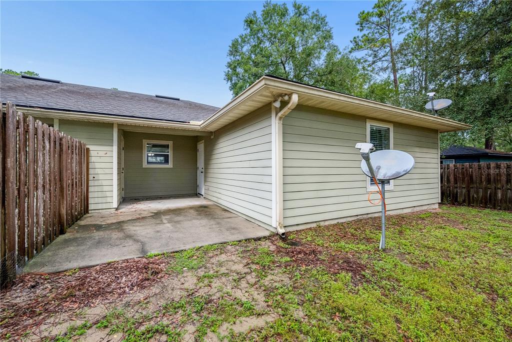 The exterior of a house features light green horizontal siding, a concrete patio, and a satellite dish — 226 BRADFORD DRIVE, STARKE, FL