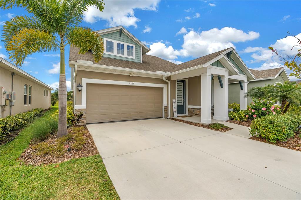 A covered porch features two wicker chairs with striped cushions and a stone-accented wall — 8217 TRIMBELLE, PARRISH, FL