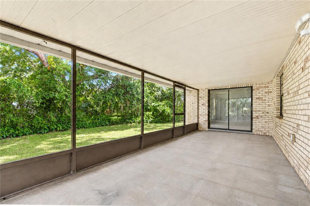 A screened-in patio with a concrete floor, white ceiling, and brick wall overlooking a yard — 716 WESTWOOD DRIVE, BRANDON, FL